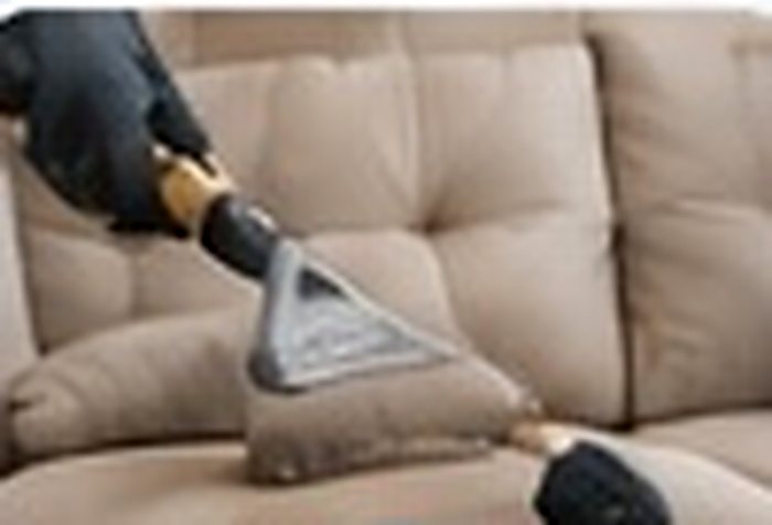 عامل ينظف كنبة قماشية بجهاز تنظيف بالبخار
